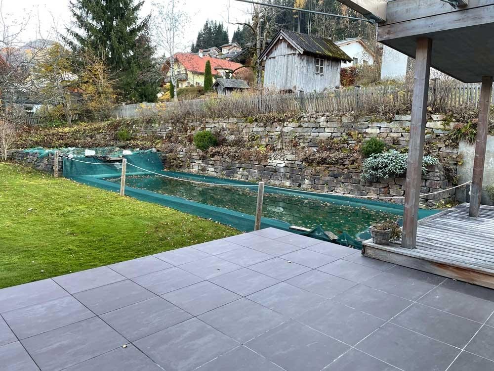 Biopool en automne avec filet de protection, terrasse et mur en pierre naturelle