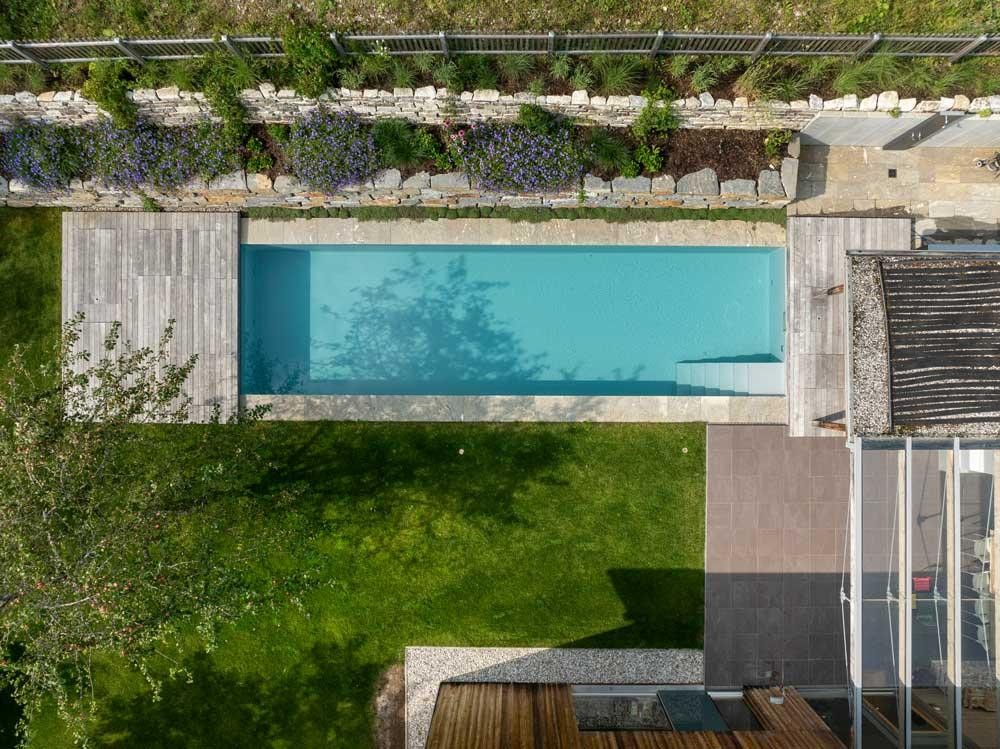 Biopool vue du dessus avec terrasse, pelouse et mur en pierre naturelle