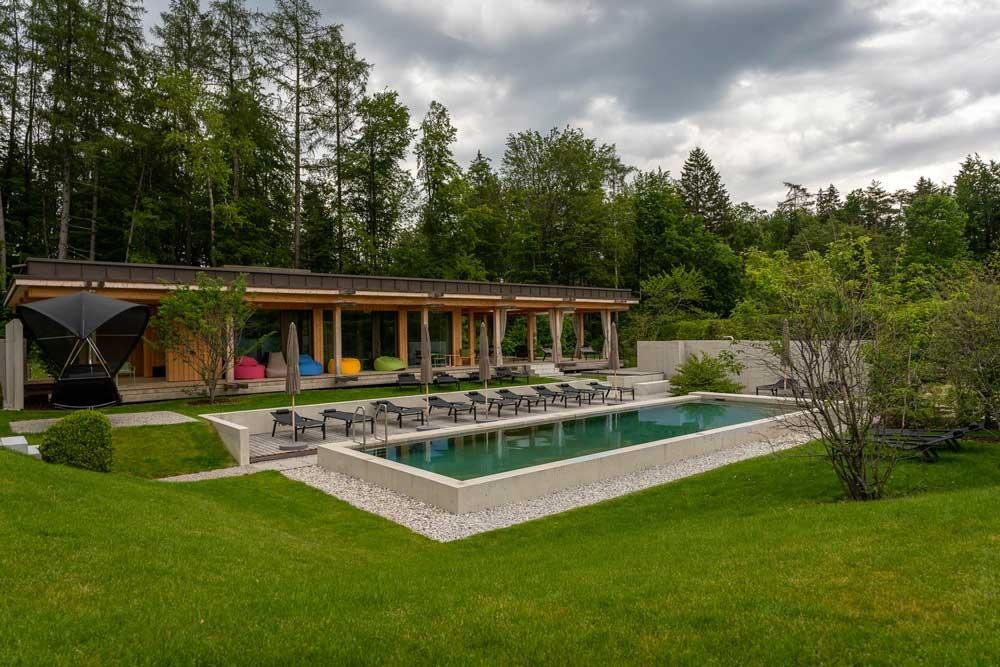 Grand biopool dans le jardin de l’hôtel avec transats et architecture moderne