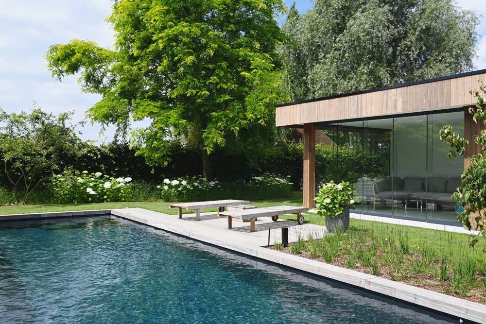 Living Pool avec poolhouse moderne dans un jardin soigné avec terrasse et piscine naturelle