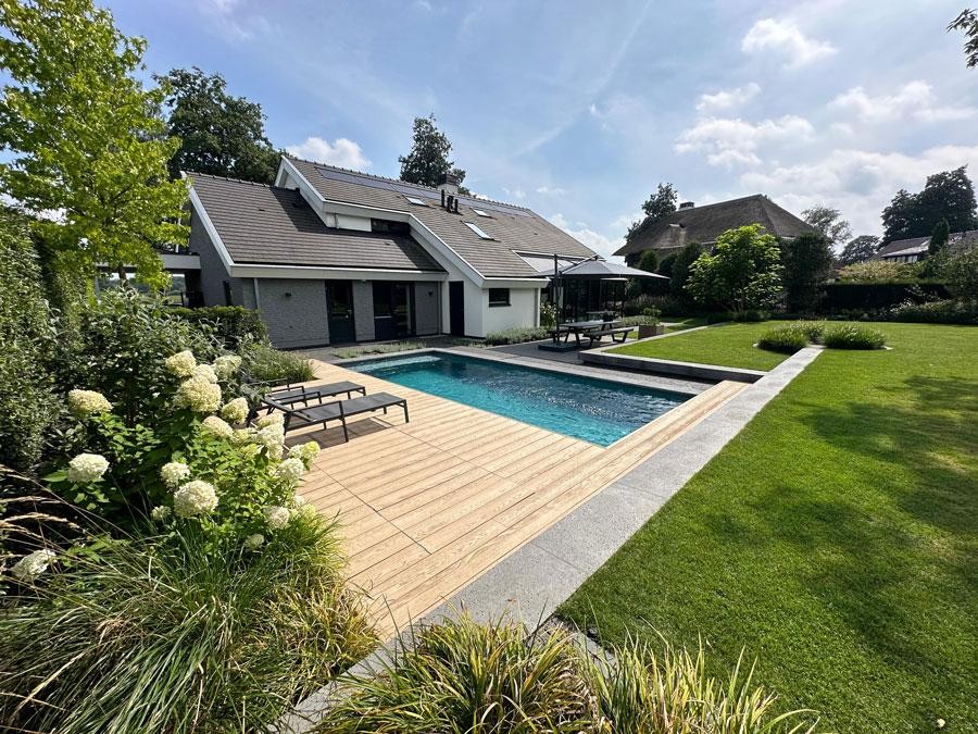 Piscine design avec terrasse en bois dans un jardin familial soigné