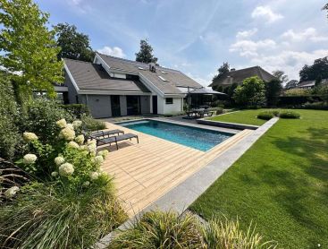 Piscine design avec terrasse en bois dans un jardin familial soigné
