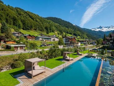 Vue aérienne d’une piscine d’hôtel dans un village alpin avec décor montagneux