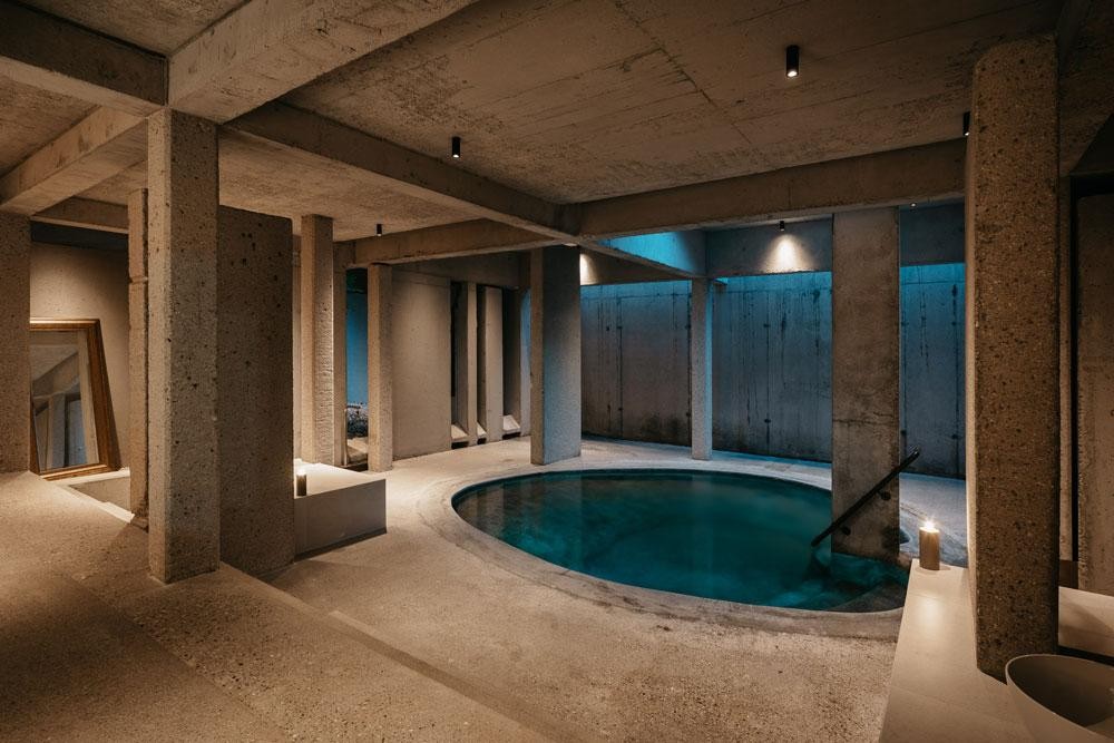 Piscine intérieure ronde avec architecture en béton et éclairage d’ambiance