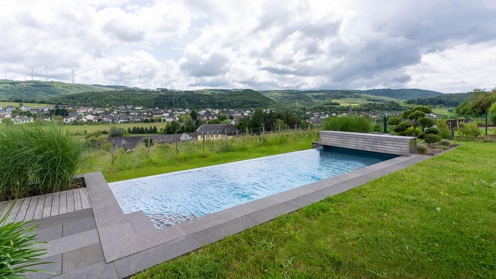 Piscine naturelle en pente avec vue dégagée sur le paysage et le village
