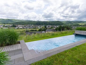 Piscine naturelle en pente avec vue dégagée sur le paysage et le village