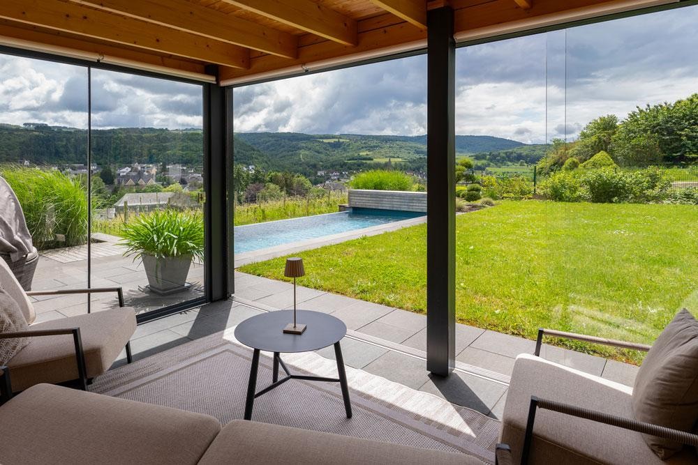 Vue depuis l’espace de vie sur une piscine naturelle et un vaste paysage