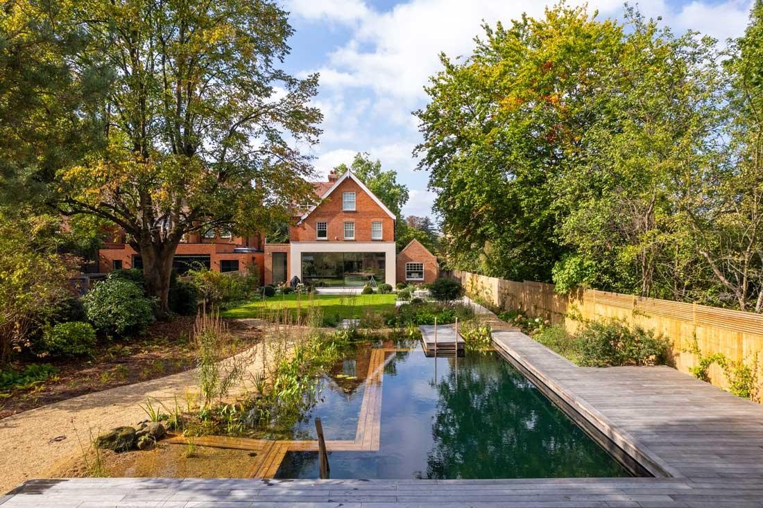 Piscine naturelle avec terrasse en bois et pavillon de jardin dans un jardin naturel
