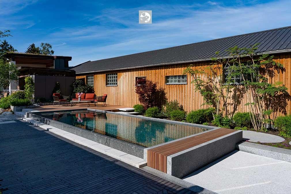 Piscine naturelle primée avec maison en bois et aménagement paysager moderne