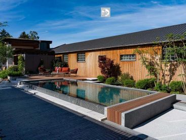 Piscine naturelle primée avec maison en bois et aménagement paysager moderne