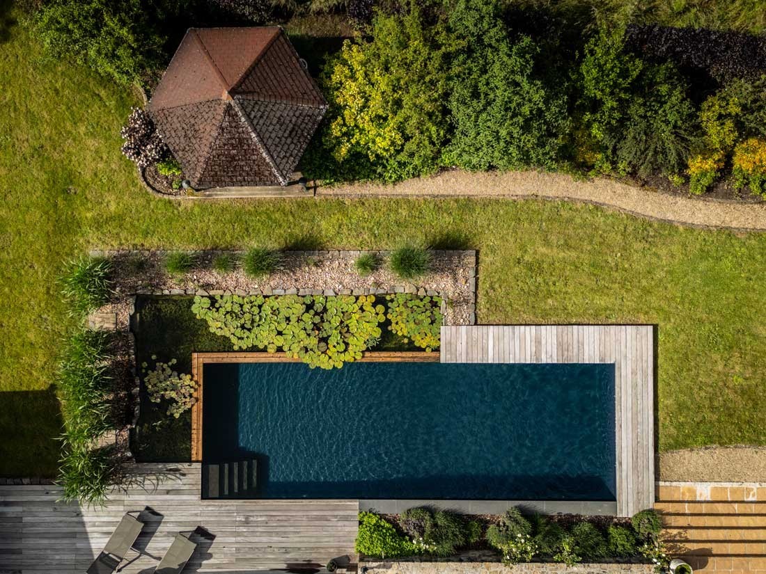 Étang de baignade avec terrasse en bois dans un grand jardin