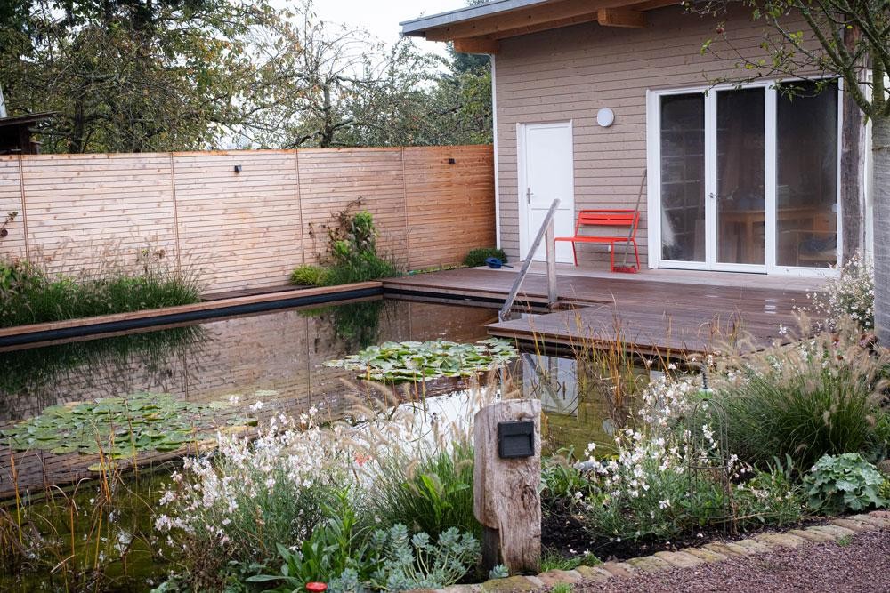 Etang de baignade avec terrasse maison en bois et jardin naturel