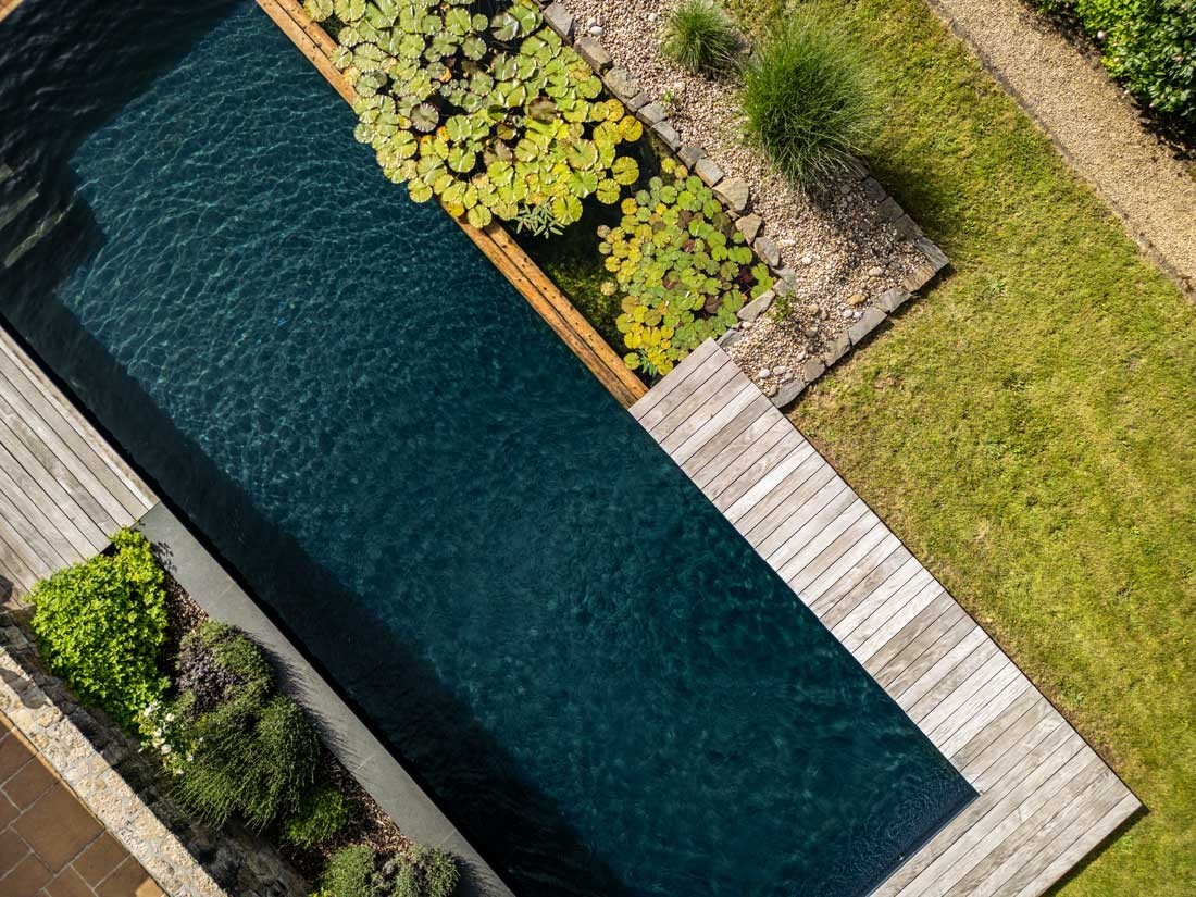 Étang de baignade vu d’en haut avec nénuphars et terrasse en bois