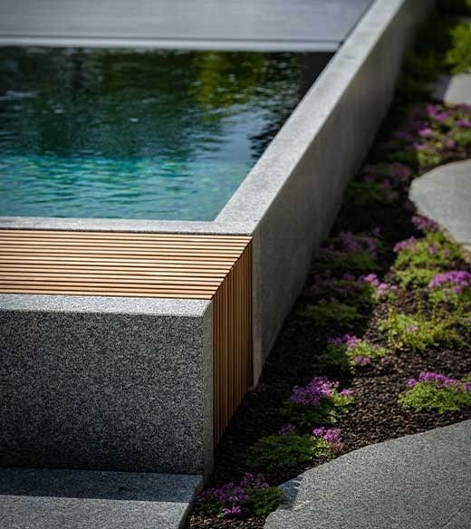 Détail de Piscine naturelle en granit avec couverture de piscine et éléments en bois