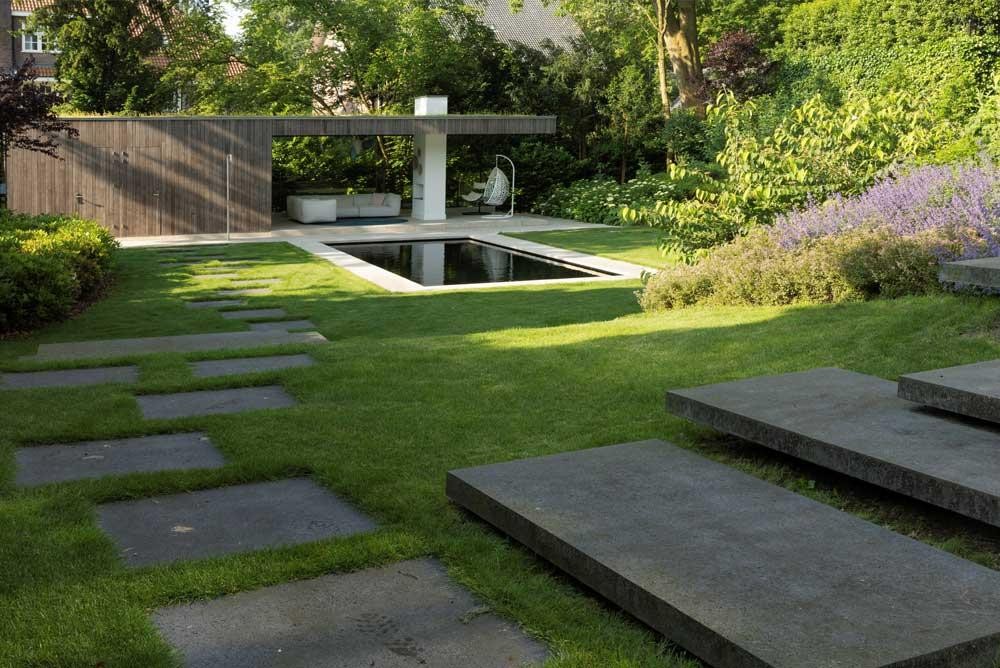 Piscine naturelle avec terrasse, pelouse et aménagement fleuri