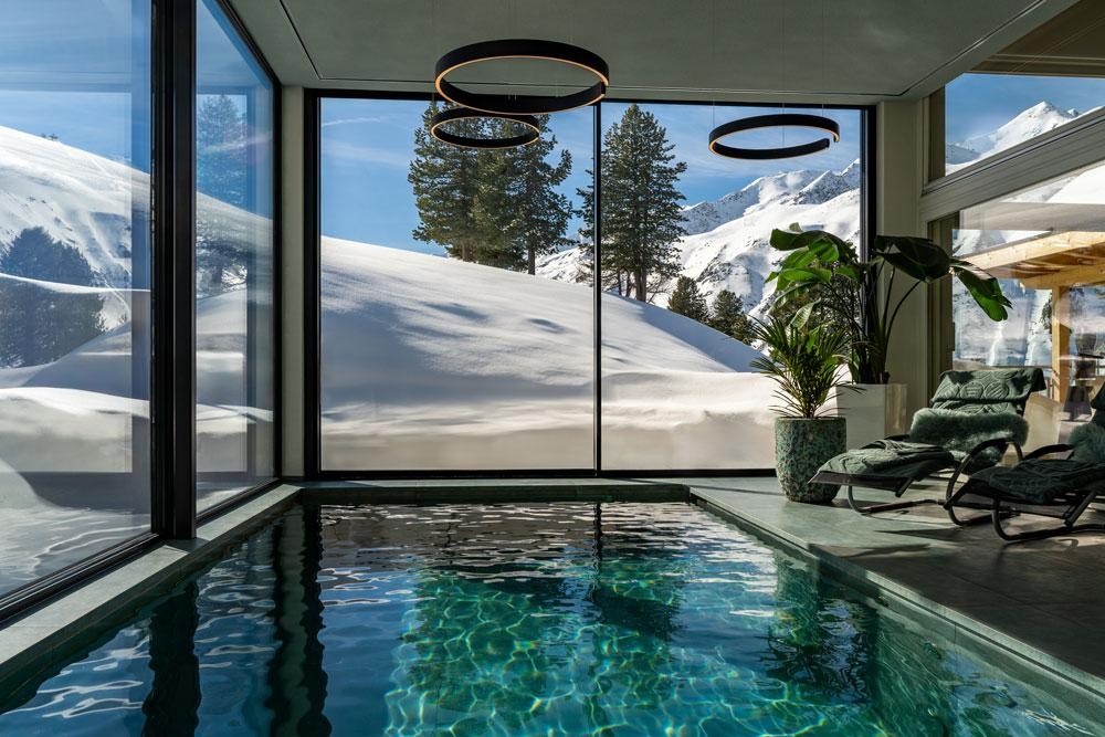 Piscine naturelle intérieure avec vue panoramique sur montagnes enneigées