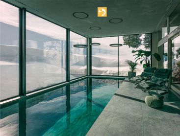 Piscine naturelle intérieure avec vue montagne et transats bien-être