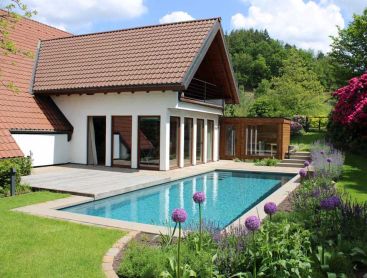 Piscine naturelle avec rhododendrons et jardin fleuri