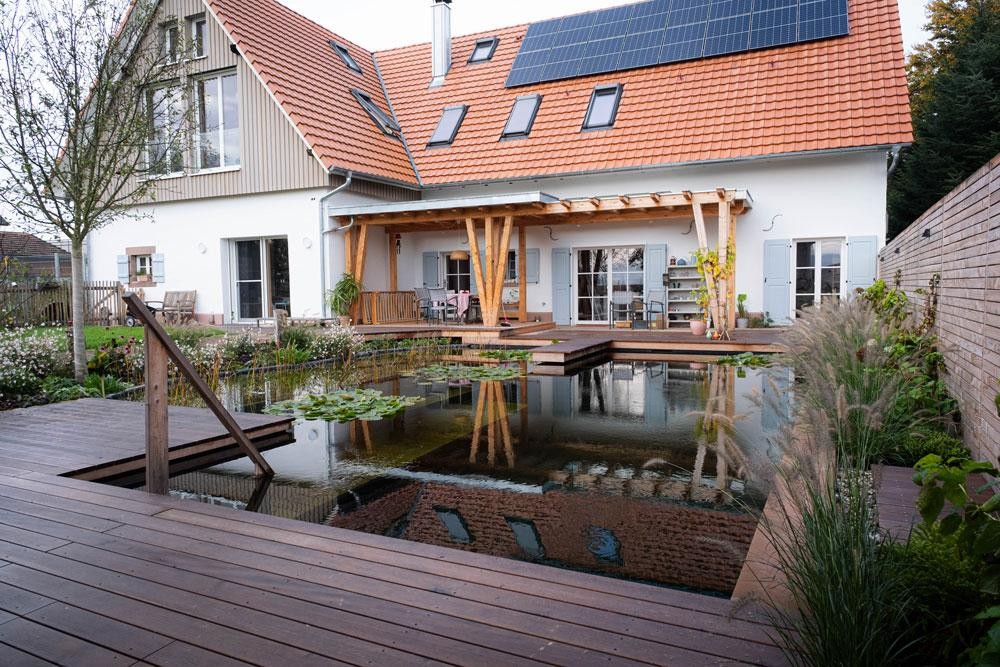 Piscine naturelle avec terrasse en bois maison moderne et toit solaire