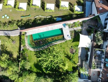 Schwimmteich von oben mit Holzdeck und naturnahem Garten
