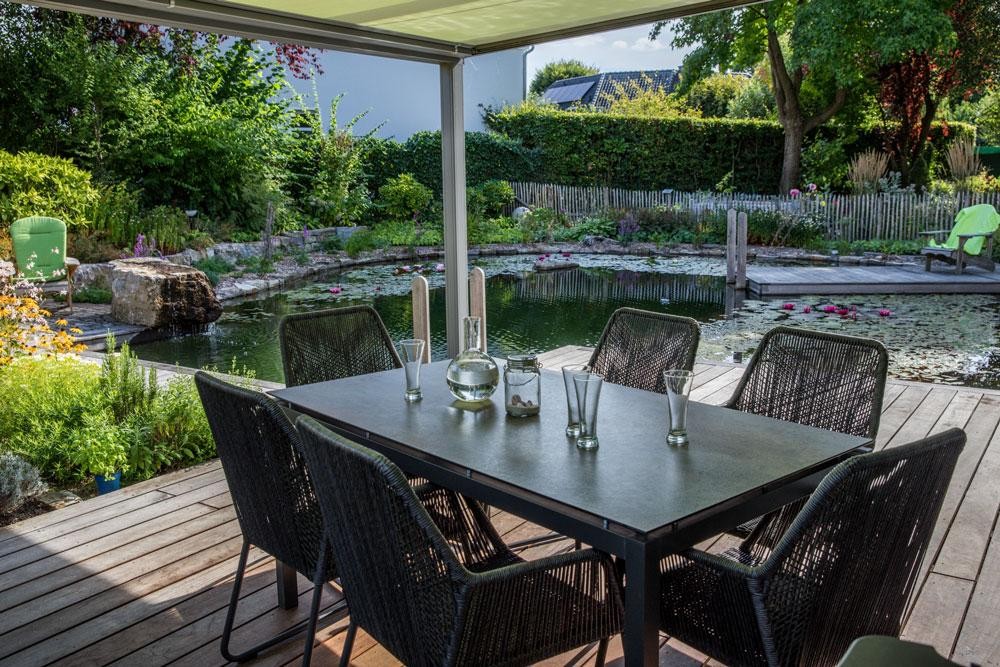 Terrasse avec table a manger et vue sur le bassin dans un jardin naturel