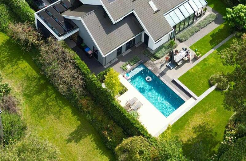 Vue aérienne d une piscine design et d'une maison individuelle dans un jardin bien entretenu